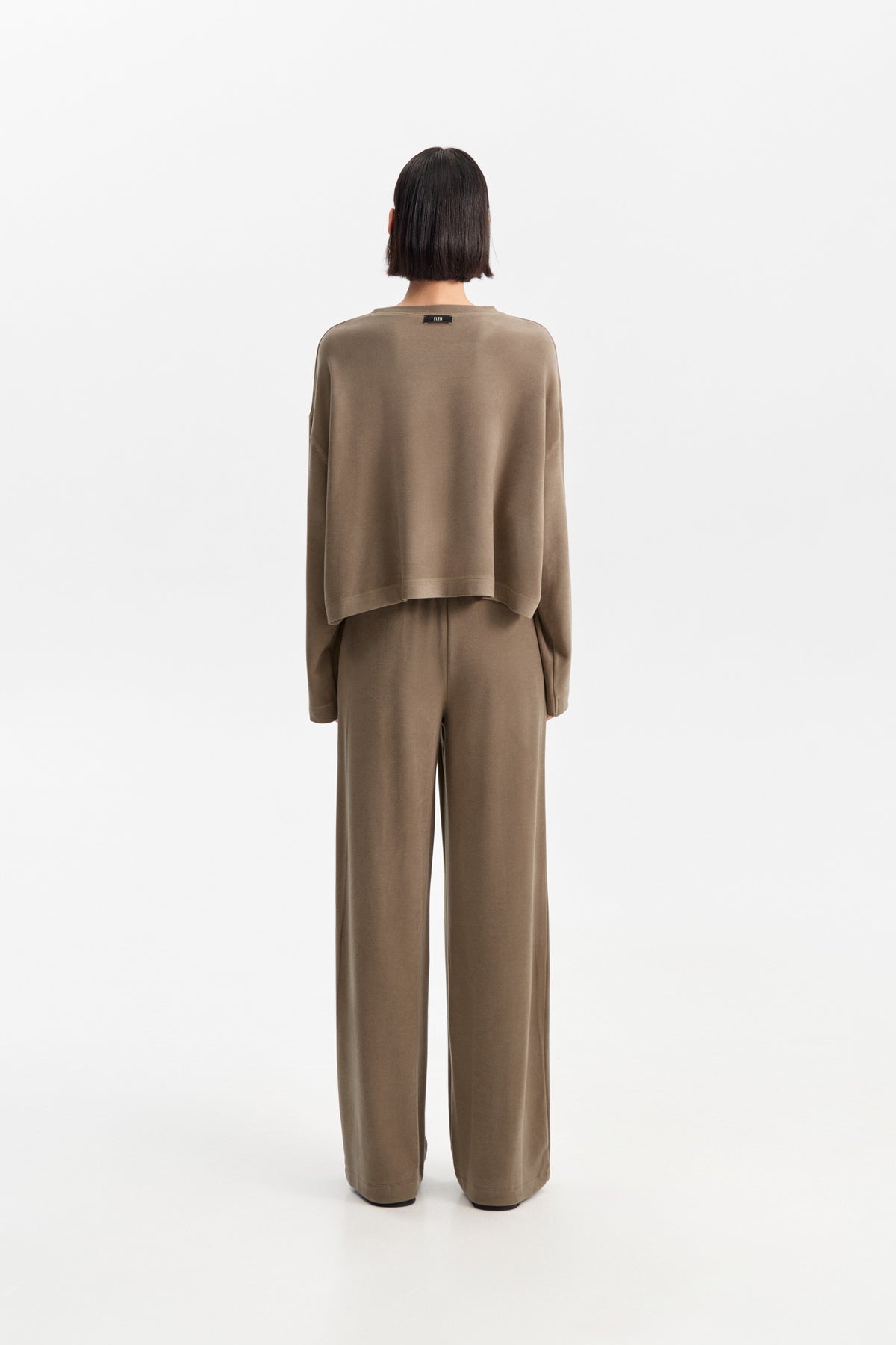 The ELEH - THE SCALA SWEATSHIRT by ELEH is a taupe, long-sleeve cropped sweatshirt featuring dropped shoulders and a relaxed fit, shown against a plain white background.