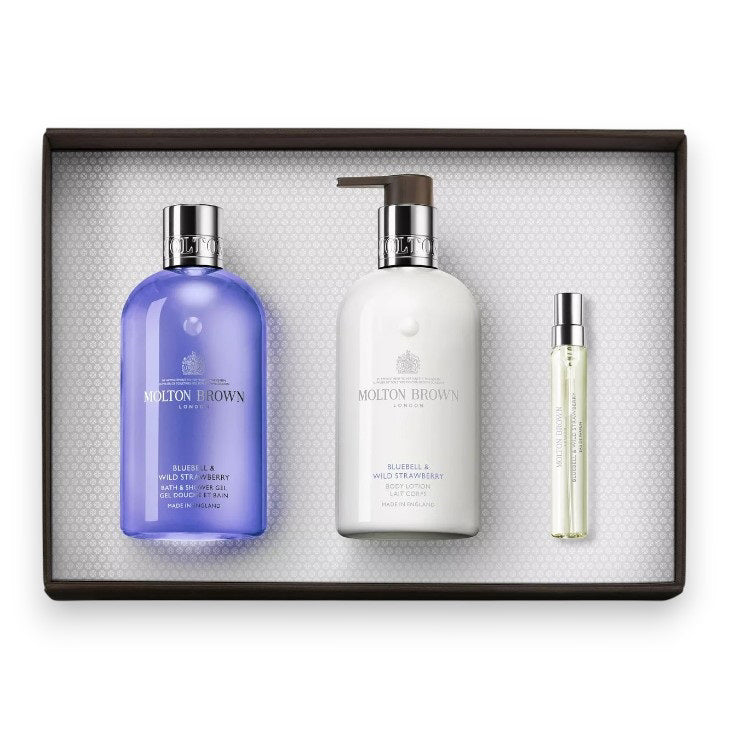 The MOLTON BROWN - BLUEBELL FRAGRANCE LAYERING GIFT SET features a Bluebell &amp; Wild Strawberry body wash, a white lotion bottle with pump, and a slim fragrance spray—elegantly presented on a white textured background.