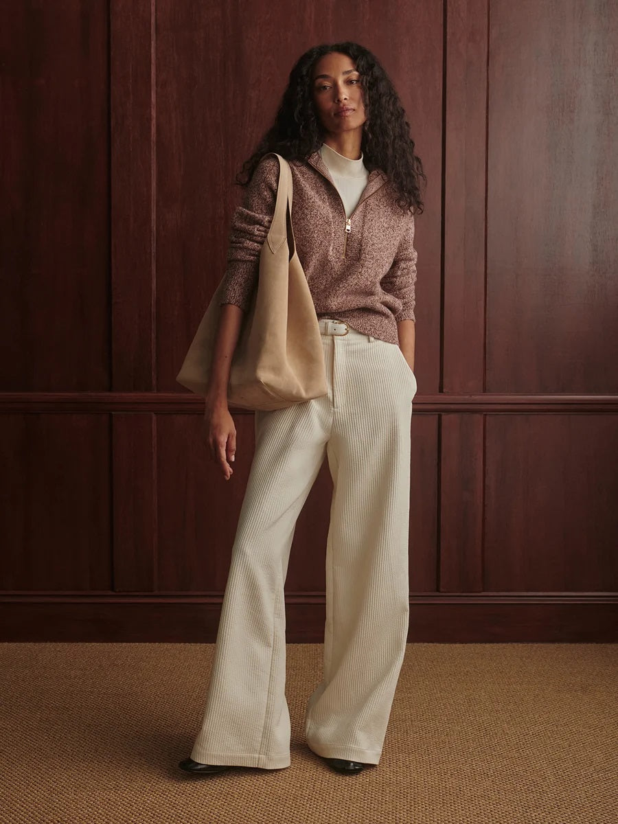 A person wearing a VARLEY - SHERIDA HALF-ZIP KNIT SWEATER IN GINGERBREAD FLECK, a brown speckled boucle yarn sweater with a collared half-zip neckline.