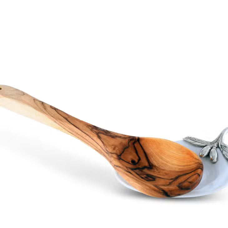 The VAGABOND HOUSE - OLIVE OIL SERVER/SPOON REST is a white, pear-shaped ceramic platter featuring a twig-like ornate metal handle adorned with pewter olives and small fruits. The handle is attached to the narrow end for an elegant touch to this minimalist design.