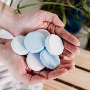 A white box labeled “BAUDELAIRE - REPLENISH EUCALYPTUS RAIN SHOWER STEAMER” by BAUDELAIRE, featuring a window that displays stacked round blue and white shower steamers inside, provides a refreshing aromatherapy experience with the invigorating scent of eucalyptus.