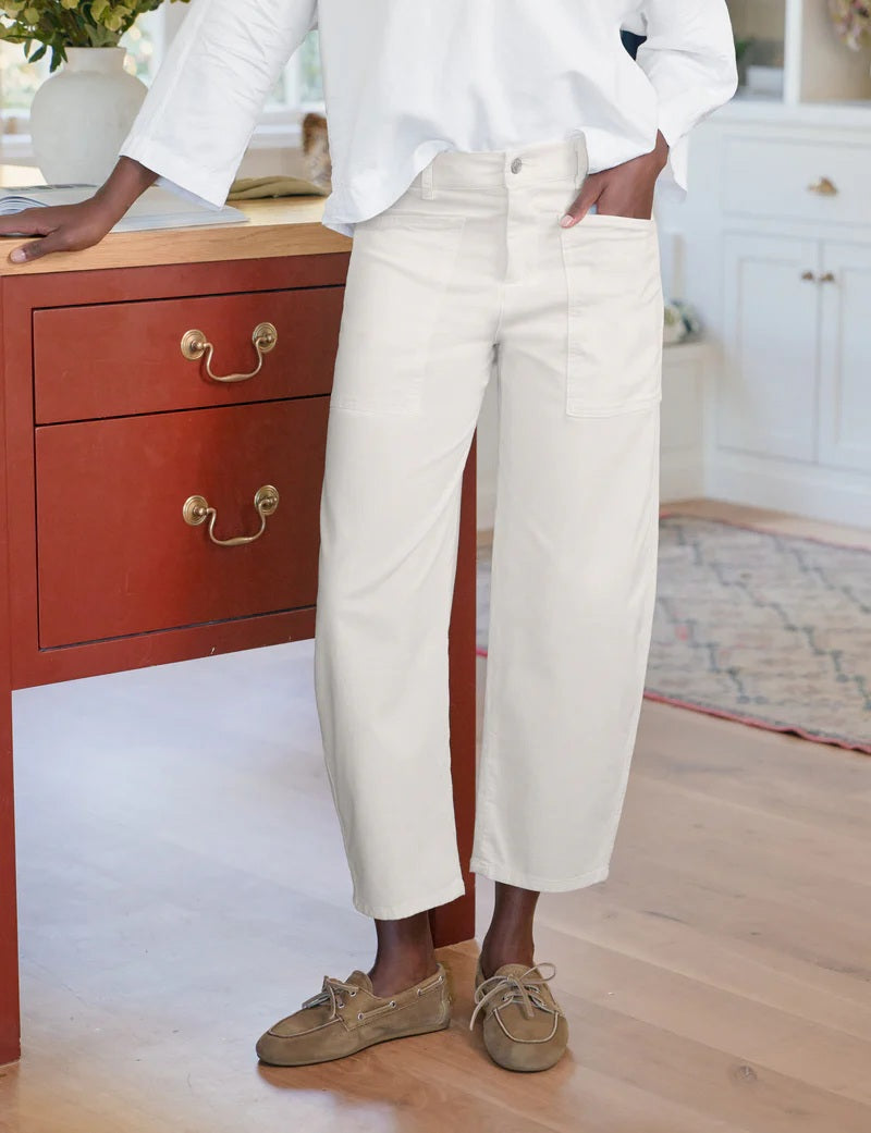 A person wearing FRANK &amp; EILEEN’s Bray Everyday Barrel Pant in Italian Peached Twill Chalk pairs them with a white long-sleeve top, standing casually with one hand in their pocket.