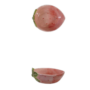 The CREATIVE COOP HAND-PAINTED STONEWARE STRAWBERRY SHAPED BOWL, SMALL features pink glaze, red dots, and a green leaf accent—a decorative piece that adds a sweet touch to your kitchen or tableware.