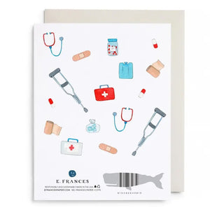 The E. FRANCES - FIRST AID KIT CARD from E. FRANCES PAPER is a watercolor greeting card featuring "Get Well Soon" in gold letters, surrounded by illustrations of crutches, stethoscopes, bandages, pills, first aid kits, pill bottles, and an ice pack on a white background—thoughtfully designed as a sympathy card and proudly made in the USA.