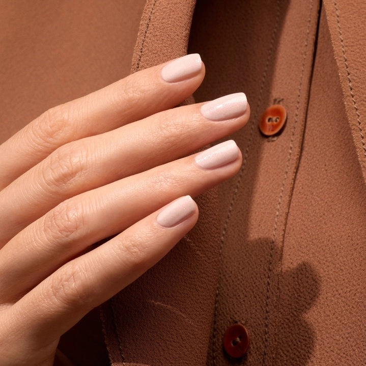 A bottle of MANUCURIST INC GREEN™ Nail Polish in Gloss, featuring a vegan, cruelty-free formula in a pale pink shade with a black cap. The label reads “green, quick dry intense color, nail polish gloss.”.