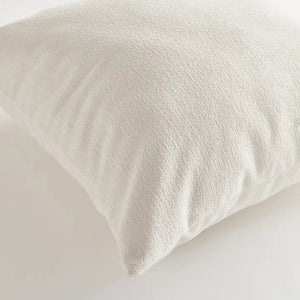 The NAPA HOME AND GARDEN - COOPER SQUARE OUTDOOR PILLOW 24" is a plain, light beige cushion with soft, textured recycled fabric. Plush and comfortable, it's ideal for sofas or beds. Shown against a white background.