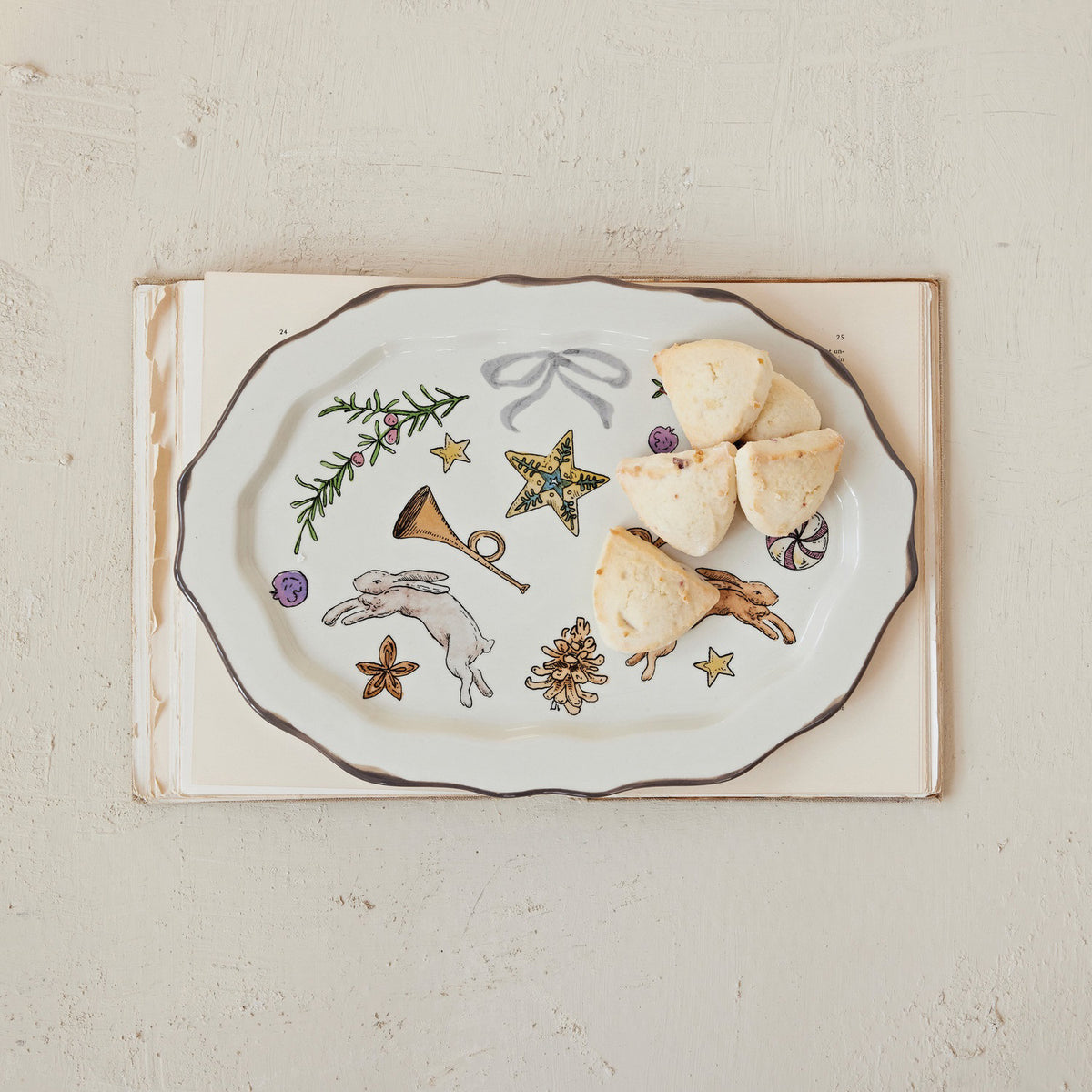 The SCALLOPED PLATTER WITH HOLIDAY MOTIF by CREATIVE COOP, featuring whimsical designs and five scones on one side, adds a charming touch to any lightly textured surface.