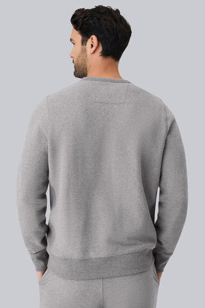 The MACK WELDON Ace Crew Neck Sweatshirt in Ice Storm Heather features long sleeves, ribbed cuffs and hem, and a small triangular stitch at the neckline, shown laid flat on a light background.