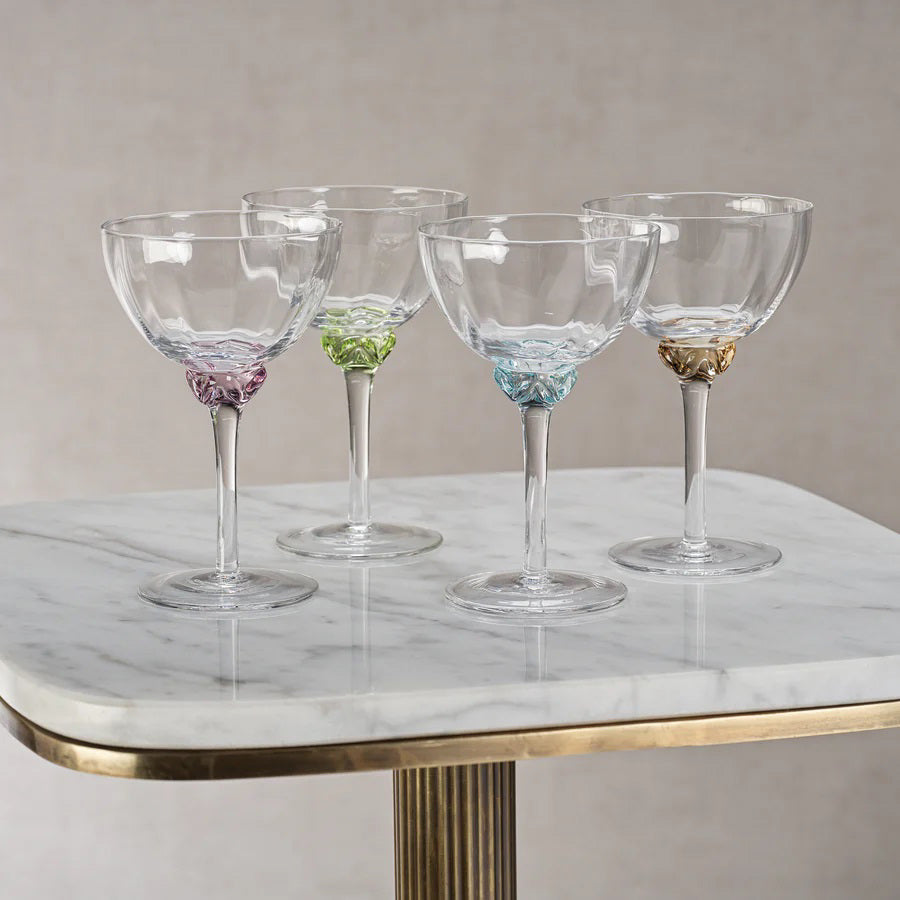 Introducing the MARTINI COCKTAIL OPTIC GLASS by ZODAX: a clear, elegant stemmed glass featuring a shallow, wide bowl. The glass boasts a detailed, decorative stem and a circular base. With a 150 ml capacity, its minimalist and sophisticated design is ideal for serving champagne or cocktails.