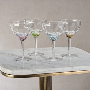 Introducing the MARTINI COCKTAIL OPTIC GLASS by ZODAX: a clear, elegant stemmed glass featuring a shallow, wide bowl. The glass boasts a detailed, decorative stem and a circular base. With a 150 ml capacity, its minimalist and sophisticated design is ideal for serving champagne or cocktails.