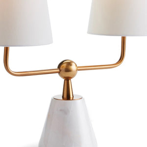 Introducing the Madison Dublet Lamp by NAPA HOME AND GARDEN, showcasing a modern design with two white conical shades on a gold bar. Its marble base and brass finish provide sophistication against a plain white background.