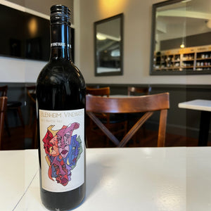 A bottle of BLENHEIM ‘PAINTED RED’ 2023 by WINE: 3 KEYS, featuring a colorful abstract label with red, blue, and yellow shapes on a light background.