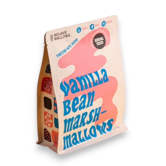 A pastel-colored bag of MOJAVE MALLOWS - VANILLA BEAN MARSHMALLOWS from MOJAVE MALLOWS, featuring bold blue and peach lettering, abstract shapes, and packaging details highlighting that these marshmallows are organic, vegan, toastable, snack-worthy, and handmade.