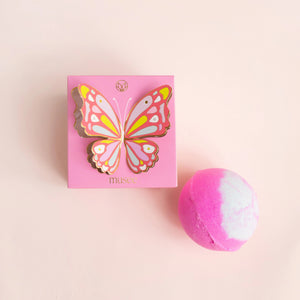 The MUSEE - BUTTERFLY BOXED BATH BALM by MUSEE, a handcrafted pink and white bath balm, sits beside its matching pink box adorned with a vibrant butterfly illustration and the “musee” logo at the bottom. Made with natural ingredients, this luxurious bath product promises a soothing and indulgent experience.