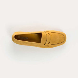 The REQINS - HEMA Suede Loafer in Ochre, expertly crafted by REQINS, features a low heel and a decorative front strap, shown against a plain light background.