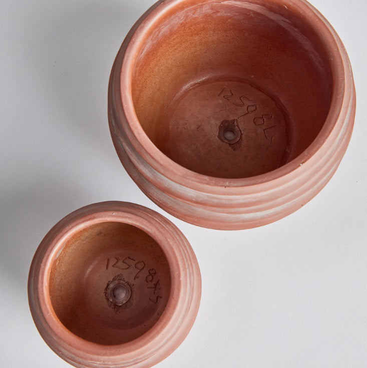 Two NAPA HOME AND GARDEN KIPHA POTS with handwritten numbers inside, shown from above on a white background. The larger, modern pot appears in the upper right, with the smaller one on the lower left.