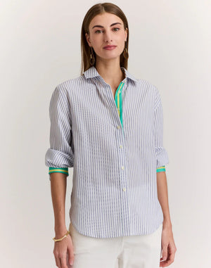 A woman with straight brown hair is shown from behind wearing the HINSON WU JULIANA Long Sleeve Shirt in Contrast Stripe, a 100% cotton blue and white vertical striped shirt with back buttons and green-trimmed sleeves, against a light background.