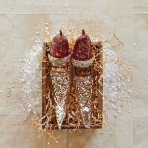 The CREATIVE COOP HAND PAINTED MERCURY GLASS SANTA MOON ORNAMENT features a crescent moon shape with a red tip, silver glitter accents, and a hanging string—perfect for adding festive charm to your Christmas tree.