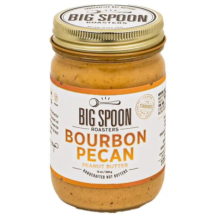 A glass jar of Big Spoon Roasters Bourbon Pecan Peanut Butter with a white label featuring a spoon icon.