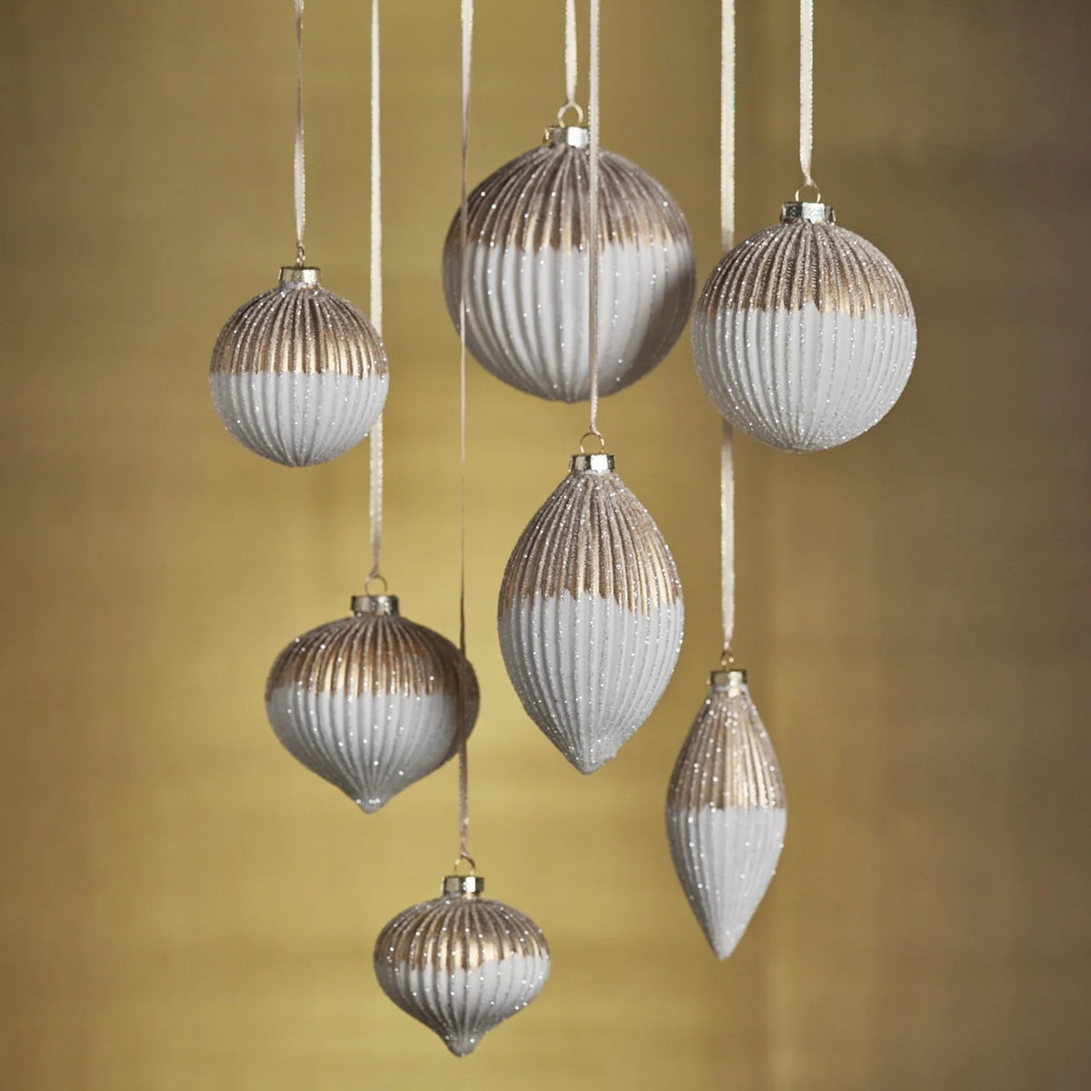 Six RIBBED TOW TONED GLASS TEAR FROP ORNAMENTs in round and teardrop shapes hang from ribbons, measuring 2.25 x 5.25 inches each with a metallic gold top half and a white glittery bottom half.