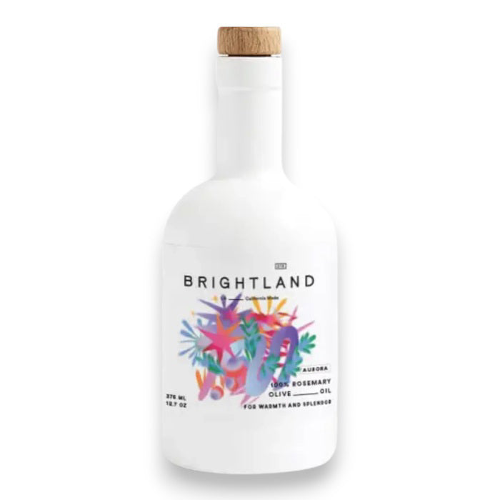 A white bottle of BRIGHTLAND - 'AURORA' Rosemary Infused Olive Oil with a wooden cap. The label features colorful abstract artwork and text that reads "Brightland" and "Aurora, cold-pressed rosemary olive oil for warmth and balance." Sourced from the California Central Coast, the bottle contains 375 ml or 12.7 fl oz.