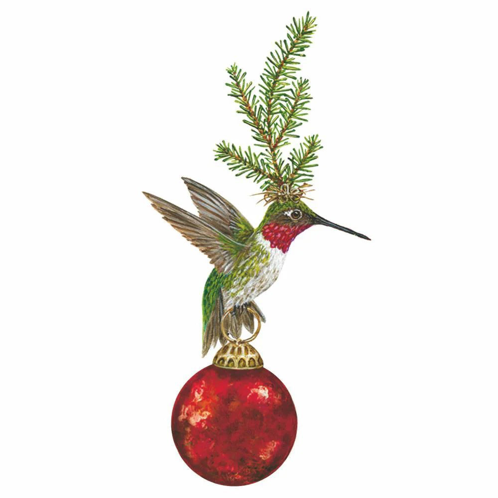 A red-throated hummingbird with green feathers perches on a shiny red ornament, holding a pine branch—ideal for festive decor or printed on PAPER PRODUCT DESIGN - FRANKLIN BEVERAGE NAPKINS by PAPER PRODUCTS DESIGN.