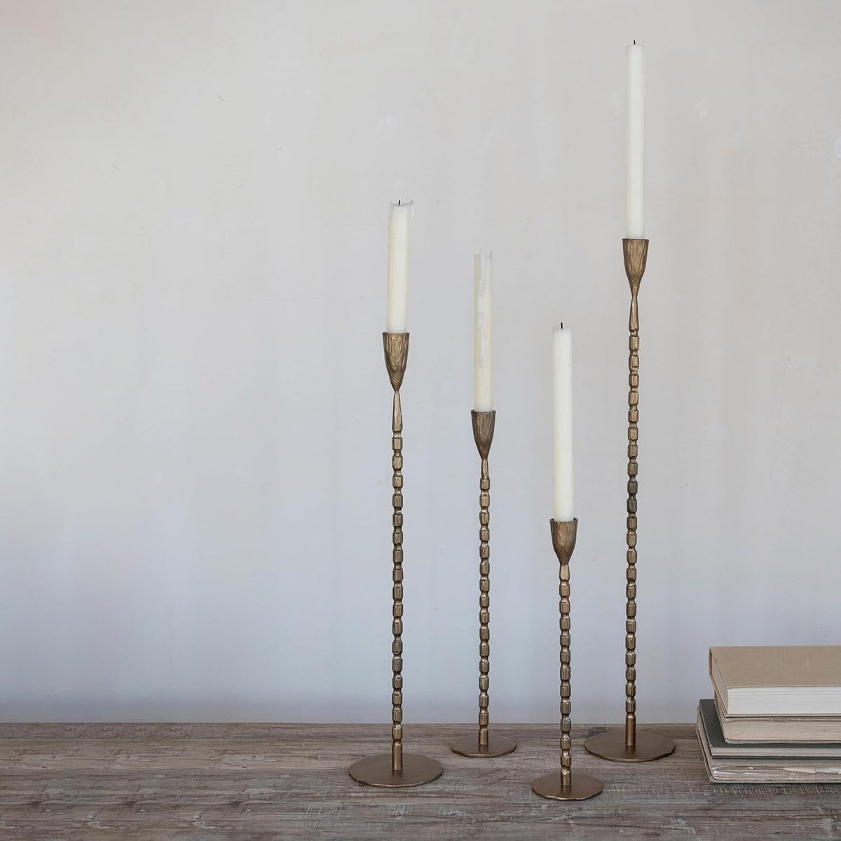 The CREATIVE COOP Cast Iron Taper Holder in Brass Finish, Small, features a slender design with a textured beaded stem and round flat base, perfect for modern minimalist decor.