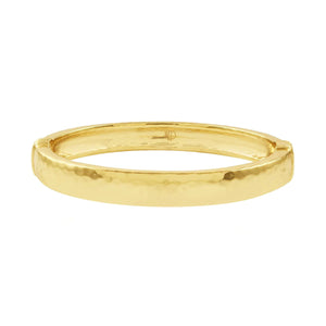 The CAPUCINE DE WULF - CLEOPATRA OVAL HINGED BANGLE SMALL/MEDIUM showcases a gleaming 18K gold plated finish with a subtly textured, hammered surface. This bangle exudes modern elegance through its simplistic, smooth oval design and reflective surface that enhances its sophisticated allure.