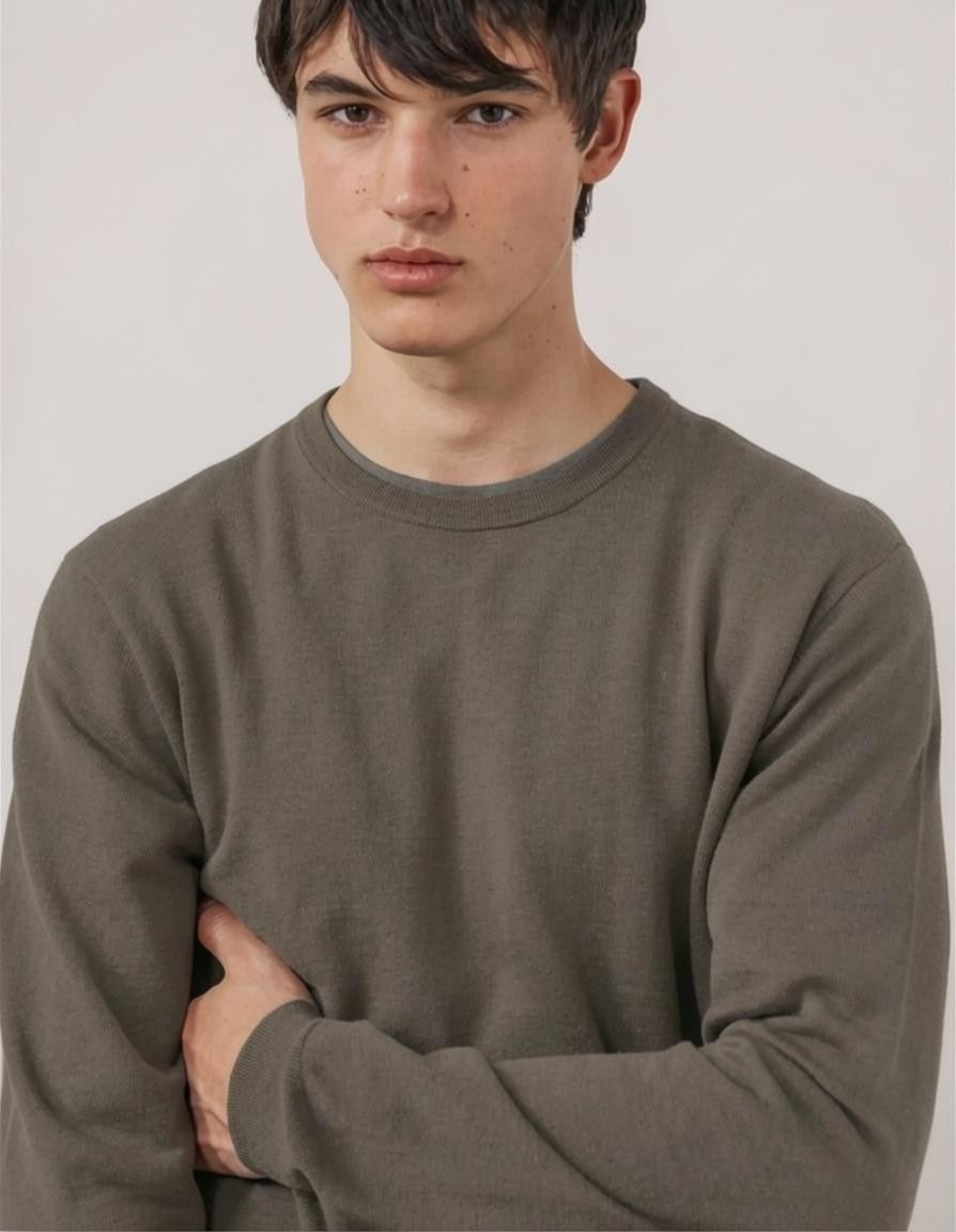 A person wearing the HARTFORD Extra-Fine Merino Wool Crew Pullover in Mushroom and beige pants stands with hands in pockets against a white background.