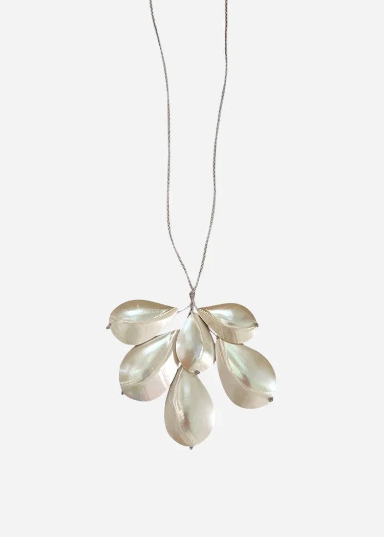The ANN LIGHTFOOT - CHAMBERED NAUTILUS SHELL SPRAY NECKLACE by ANN LIGHTFOOT is showcased on a white jewelry bust against a plain white background. Reminiscent of an elegant spray necklace, this piece features overlapping metallic chambered nautilus shell pendants suspended from an adjustable sleek black nylon cord.