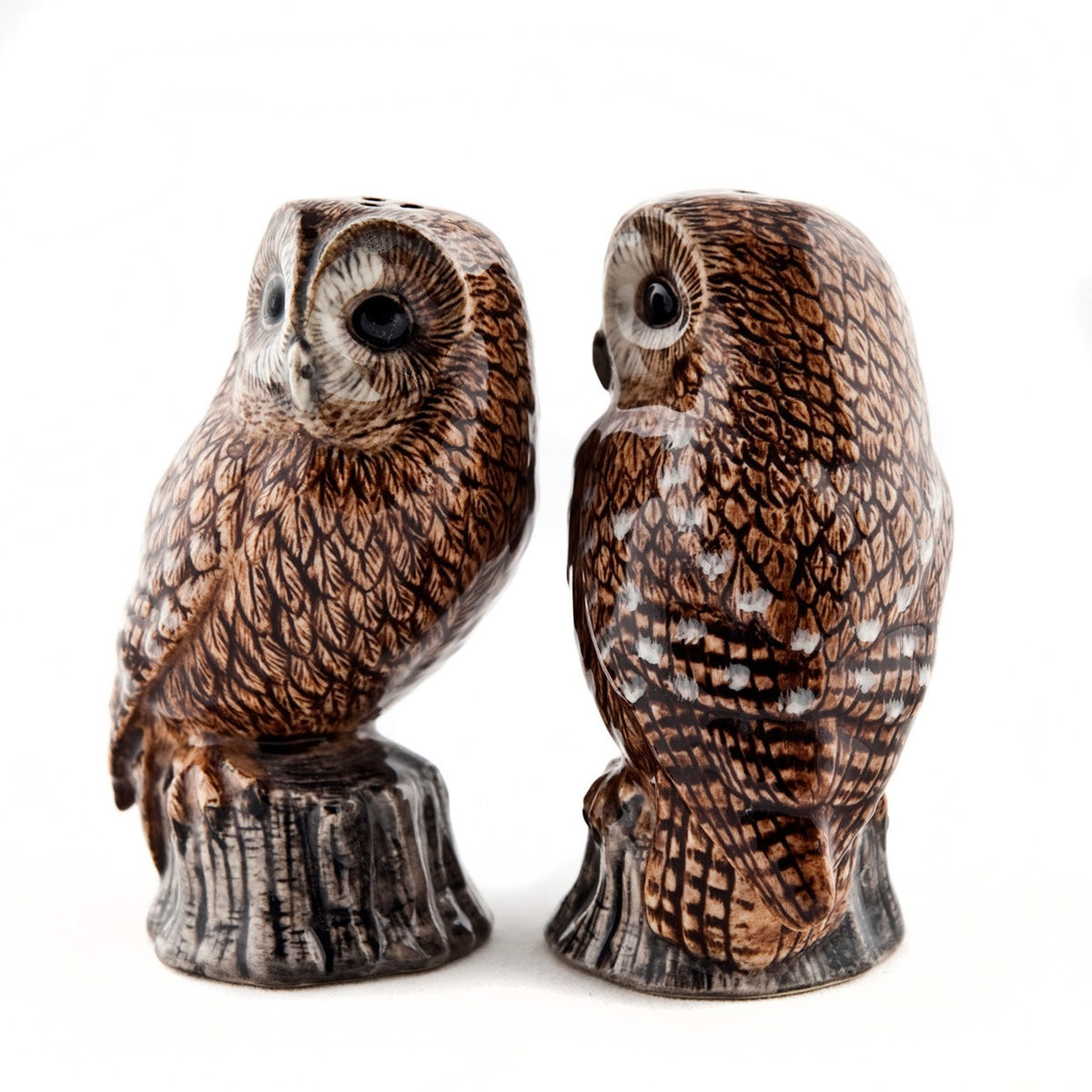 The QUAIL CERAMICS - TAWNY OWL SALT AND PEPPER SET by QUAIL DESIGNS features two brown and white stoneware owl shakers on gray tree-stump bases—ideal for adding a charming touch to your table.