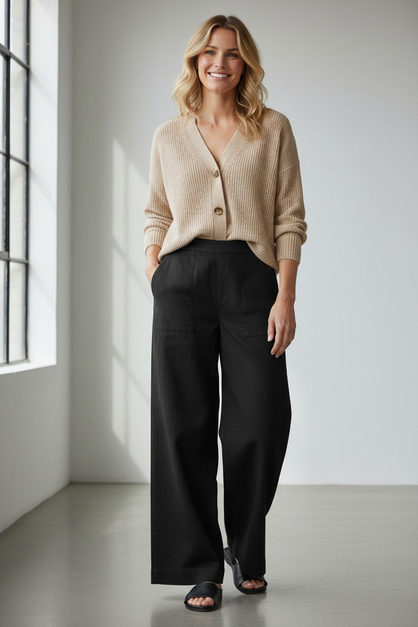 A person wearing the FRANK &amp; EILEEN Madeline Patch Pocket Pull On Pant in Famous Denim Black styled with a beige knit sweater, shown from waist to mid-thigh.
