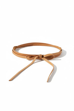 The ADA - SKINNY WRAP BELT by ADA is a thin, light brown leather belt made from natural material. It features a simple front knot and has adjustable ends that hang down, shown laid flat on a white background.