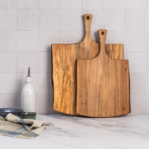 The SPENCER PETERMAN Live Edge Spalted Ambrosia Maple Serving Board 21" by Petermans Boards & Bowls Inc is a rectangular, handcrafted serving board with a handle and a hole for hanging, displayed on a white background.