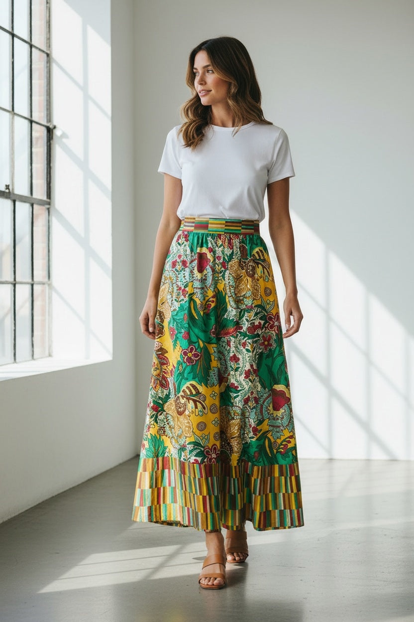 The MOMONI - IRIS SKIRT by MOMONI features vibrant yellow, green, and red floral prints on poplin with a geometric striped waistband and hem. Its flowy A-line silhouette offers effortless style.