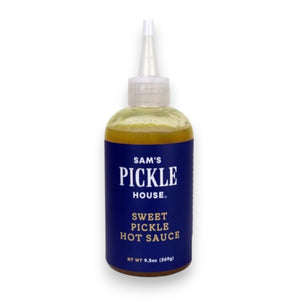 A squeeze bottle labeled “THE PICKLE HOUSE - SWEET PICKLE HOT SAUCE” features a dark blue label with white text. The bottle holds a greenish-yellow, sweet and hot sauce that’s ideal as a salad dressing and comes with a pointed nozzle cap.