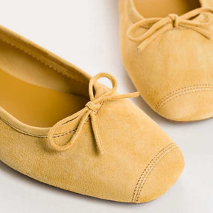 REQINS - HARMONY SUEDE BALLERINA FLATS IN OCHRE: a pair of ochre suede ballet flats with a small bow detail at the toes.