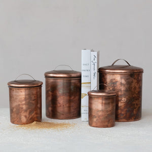 A top view of the CREATIVE COOP STAINLESS STEEL CANISTERS IN OXIDIZED COPPER FINISH, SET OF 4, featuring matching copper lids and arranged symmetrically on a white background.
