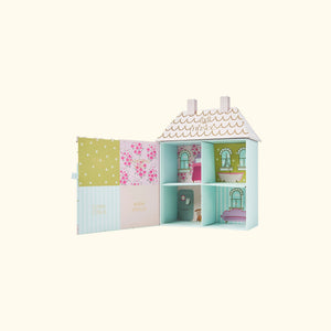 The MUSEE Dollhouse Bath Balm Set by MUSEE features a pastel-colored, house-shaped box with pink doors, six arched windows, gold roof detailing, and charming floral accents. “Anksee” is written in gold above the windows. Perfect as a children’s bath gift, this delightful packaging holds handcrafted natural bath products to make bath time extra special—all set against a light cream background.