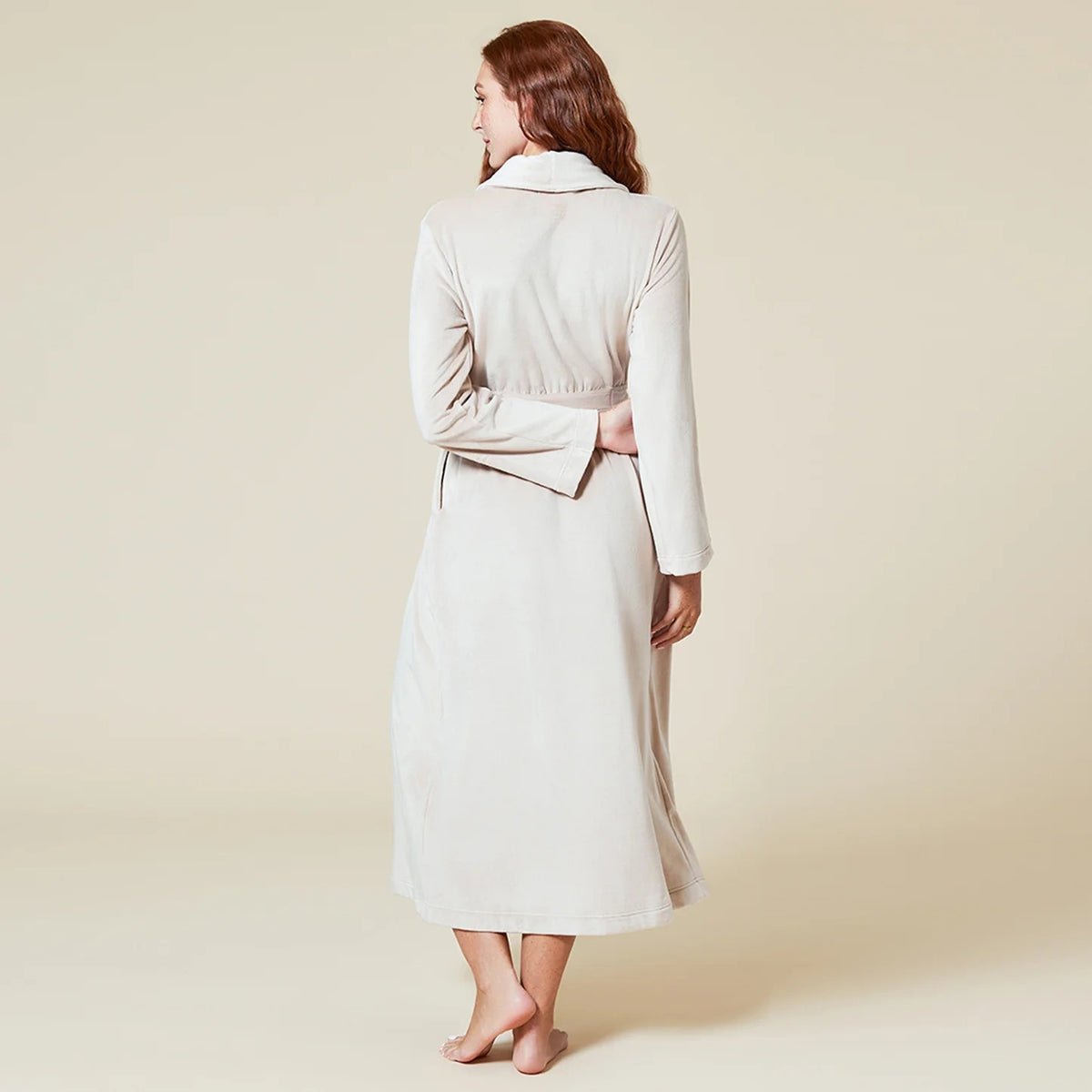 A person wearing a beige SOFTIES - SERENITY WRAP ROBE featuring a wrap silhouette with a tie waist and side pockets.
