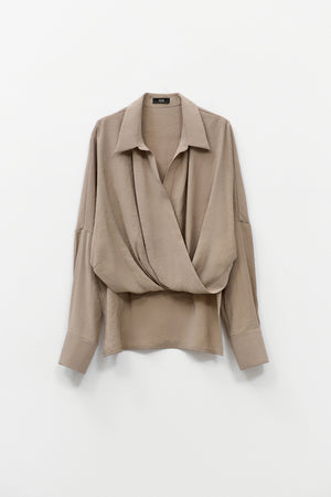 The ELEH - DRAPE FRONT BLOUSE by ELEH is a taupe Italian cotton top with a draped crossover front, wide cuffs, and a loose fit, shown against a plain white background.