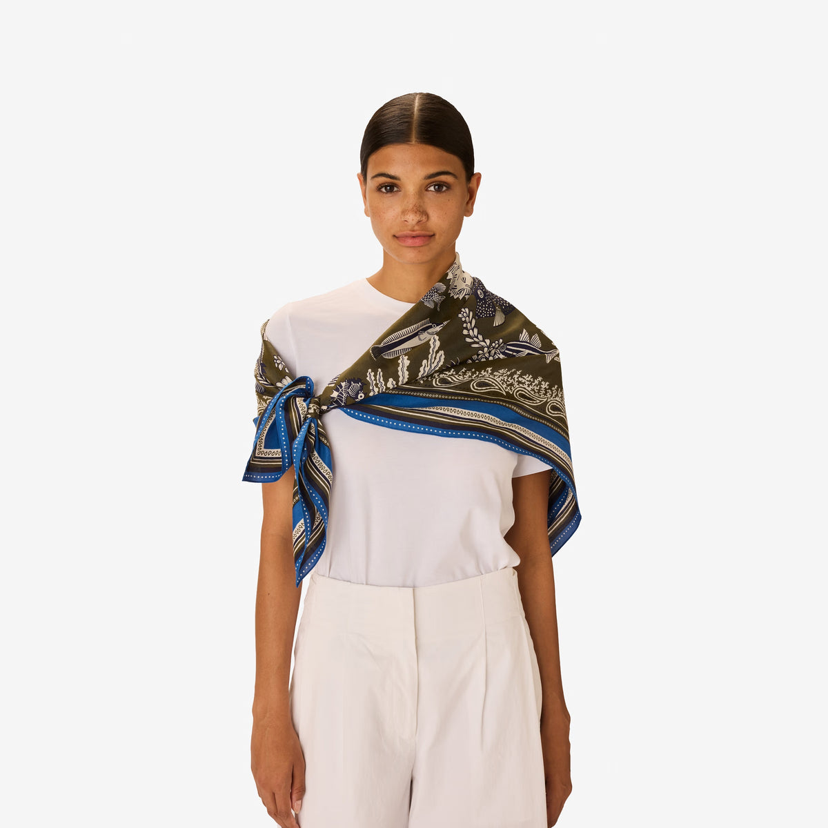 The INOUI EDITIONS - NEPTUNE SCARF IN KHAKI by INOUI features an intricate underwater scene with fish, seaweed, and coral in blue, white, and purple, bordered by geometric blue and green patterns.