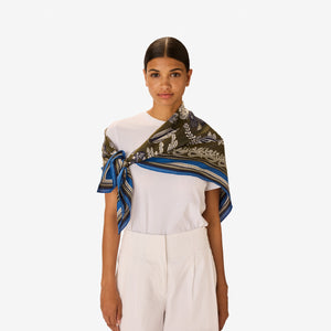 The INOUI EDITIONS - NEPTUNE SCARF IN KHAKI by INOUI features an intricate underwater scene with fish, seaweed, and coral in blue, white, and purple, bordered by geometric blue and green patterns.