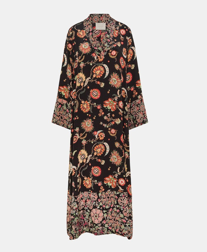 The MOMONI - FELICIEN DRESS by MOMONI is a long-sleeved, ankle-length black crepe de chine dress with a vibrant floral and paisley print in red, orange, and green, finished with patterned borders at the hem and cuffs.