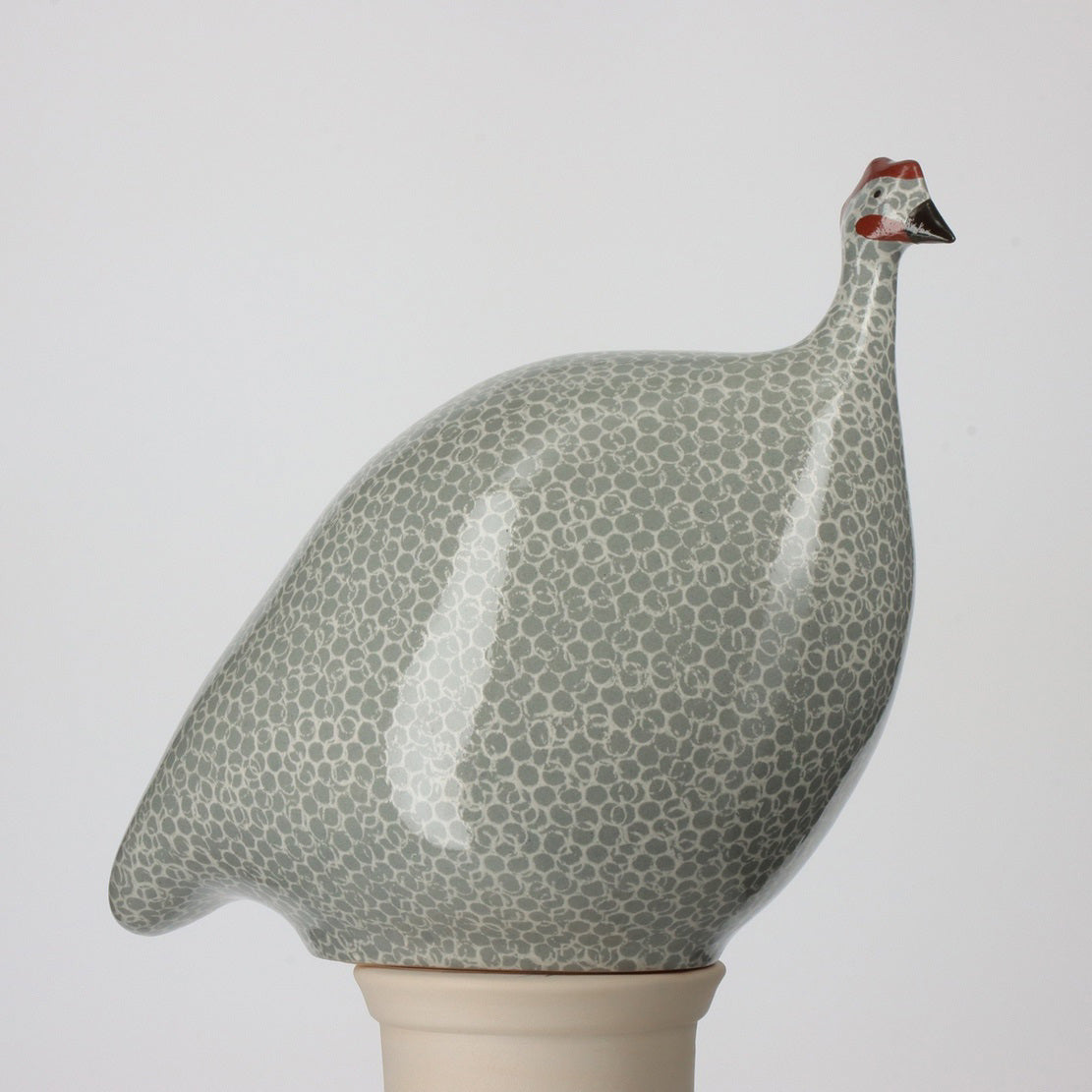 Three ceramic French guinea hens from Les Ceramiques de Lussan (sizes: 24 cm, 20 cm, 17 cm) in polar blue speckled white stand beside a handmade black pottery mug labeled &quot;MUG,&quot; which is 8.5 cm tall, against a subtle gray backdrop.