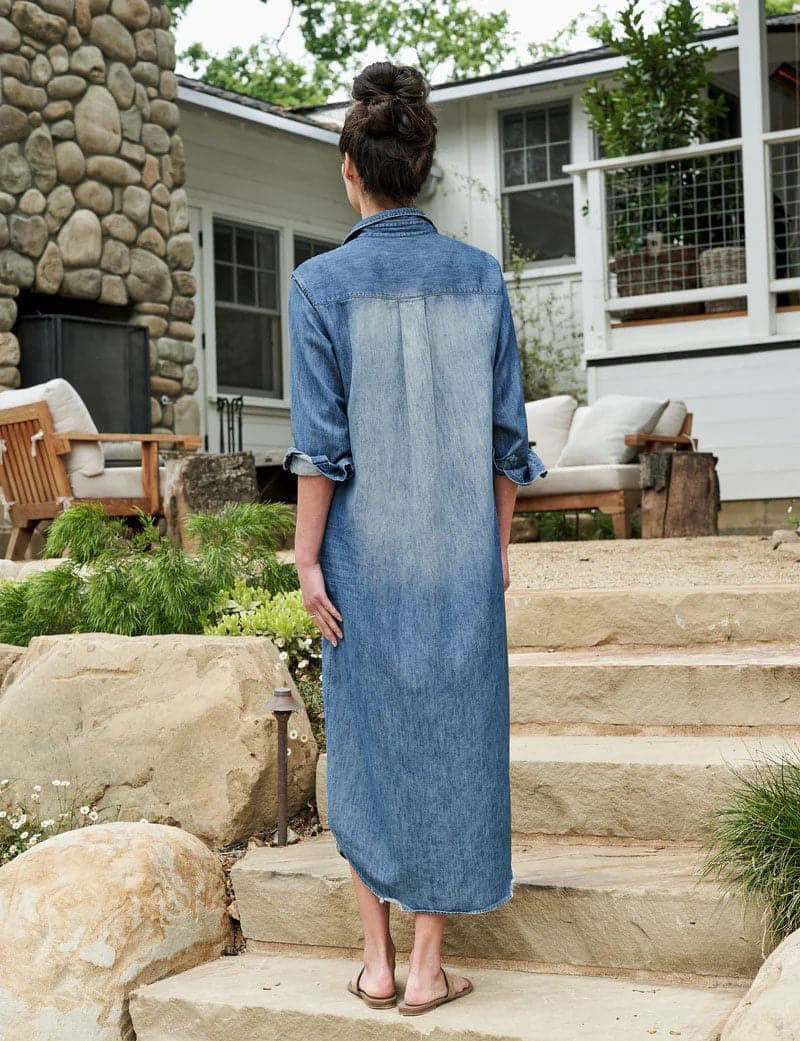 The FRANK &amp; EILEEN Rory Maxi Shirtdress in Famous Denim is a full-length button-up dress featuring a collar, rolled-up sleeves to mid-length, and a single chest pocket. Its sleek, minimalist design embodies that California chic look against a plain white textured background.