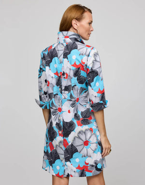 The person is wearing the HINSON WU Aileen dress, featuring a knee-length cut in stretch polished cotton with a pop art flower print in blue, black, white, and red. It has a collared neckline and three-quarter sleeves, stylishly set against a plain gray background.
