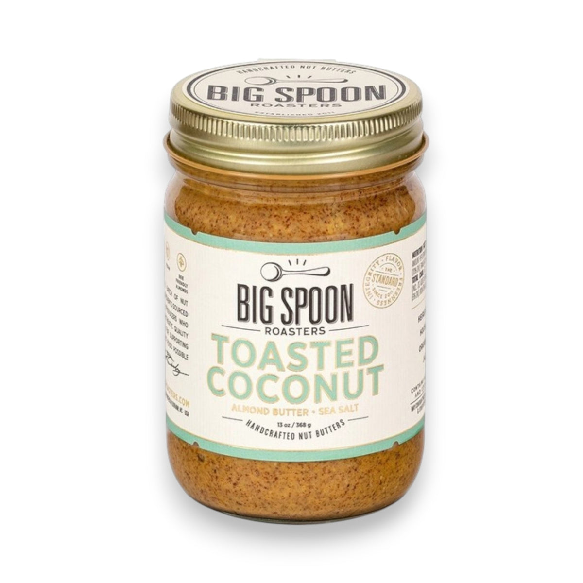 A jar of BIG SPOON ROASTERS' Toasted Coconut Almond Butter features a gold lid with a white and green label by the brand. Made with Heirloom Mission Almonds, it contains organic coconut nectar blended into light brown textured almond butter.