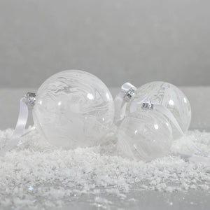 The ZODAX WATERCOLOR GLASS ORNAMENT IN WHITE is a round, marbled 4-inch Christmas ornament suspended by a thin silver ribbon against a plain white background.