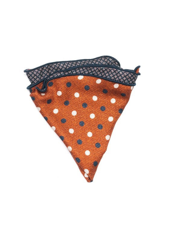 The EDWARD ARMAH Silk Reversible Pocket Circle Rust Polka Dot, featuring white and navy accents with a navy patterned edge, is displayed flat on a white background.